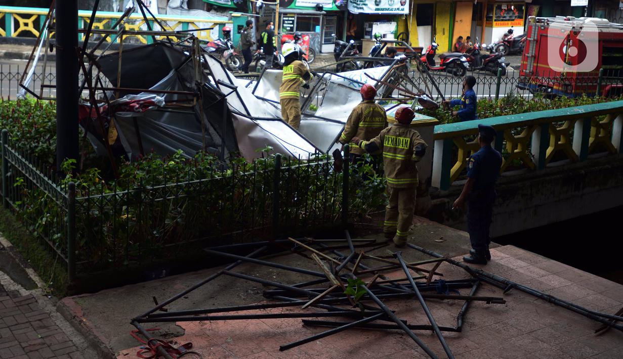 Petugas pemadam kebakaran memotong rangka reklame di Jalan Soepomo, Jakarta, Sabtu (28/5/2022). Hujan disertai angin kencang pada pagi tadi membuat papan reklame roboh sehingga membuat kemacetan arus lalu lintas di jalan tersebut. (merdeka.com/Imam Buhori)