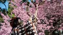 Seorang perempuan muda mengambil foto boneka saat orang-orang keluar ke Taman Ueno untuk melihat bunga sakura awal di Tokyo pada 14 Maret 2023. Pengunjung taman Ueno di Tokyo menikmati bunga sakura yang mekar lebih awal dari biasanya pada musim ini.  (Photo by Richard A. Brooks / AFP)