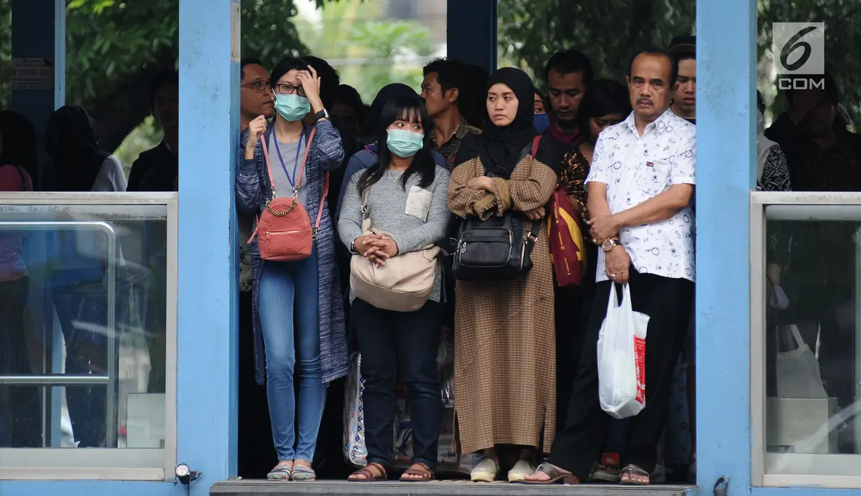 Warga menunggu bus Transjakarta di halte Bundaran Senayan, Jakarta, Jumat (14/7). Menurut Kepala Dinas LHK DKI Jakarta Isnawa Adji, kualitas udara yang buruk terjadi di hampir seluruh Jakarta terutama di pusat industri. (Liputan6.com/Helmi Fithriansyah)
