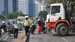 Petugas kepolisian mengatur lalu lintas akibat truk mengalami patah as di Jakarta, Selasa (29/9/2015). Imbas dari truk bermuatan alat berat mengalami patah as itu, Jalan Sudirman mengarah ke Jalan MH Thamrin terpantau padat. (Liputan6.com/Gempur M Surya)