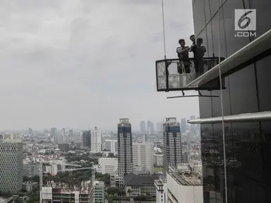 Pekerja tanpa helm keselamatan beraktivitas di gedung bertingkat di Jakarta, Rabu (15/11). Banyak kejadian kecelakaan kerja di ketinggian disebabkan karena minimnya pengetahuan dasar mengenai keselamatan kerja di ketinggian. (Liputan6.com/Faizal Fanani)