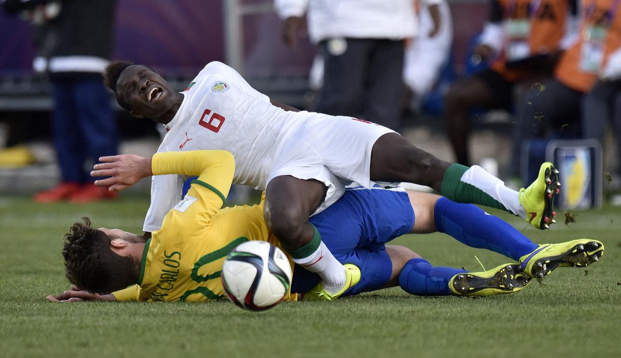 Pemain Senegal, Elimane Cisse (atas) terjatuh setelah ditekel pemain Brasil, Jean Carlos dalam laga semifinal Piala Dunia U-20 2015 di Christchurch Stadium, Selandia Baru (17/6/2015). Kesuksesan Senegal di ajang Piala Dunia U-20 ditandai dengan keberhasilan mereka menempati peringkat keempat pada edisi 2015 di Selandia Baru setelah kalah 1-3 dari Mali dalam laga perebutan tempat ketiga. (AFP/Marty Melville)