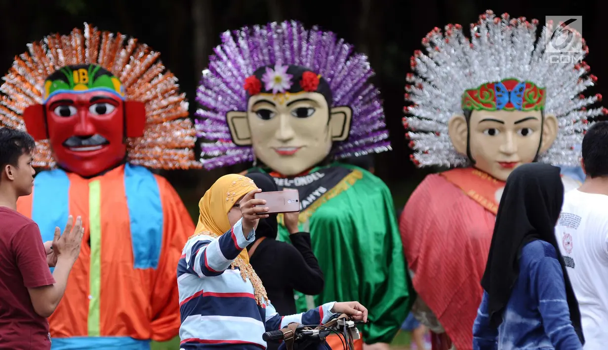 Warga berswafoto di depan deretan ondel-ondel di kawasan silang Monumen Nasional, Jakarta, Minggu (26/11). Deretan ondel-ondel ini bagian kemeriahan Kirab Kebangsaan yang diadakan Bamus Betawi. (Liputan6.com/Helmi Fithriansyah)