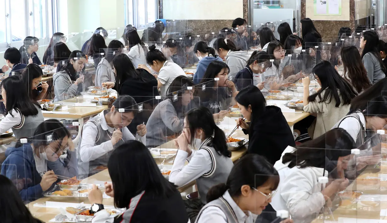 Siswa senior makan siang di meja yang dilengkapi dengan pembatas plastik untuk mencegah penyebaran virus corona baru di kafetaria di Jeonmin High School di Daejeon, Korea Selatan, Rabu, (20/5/2020). (Kim Jun-beom/Yonhap via AP)