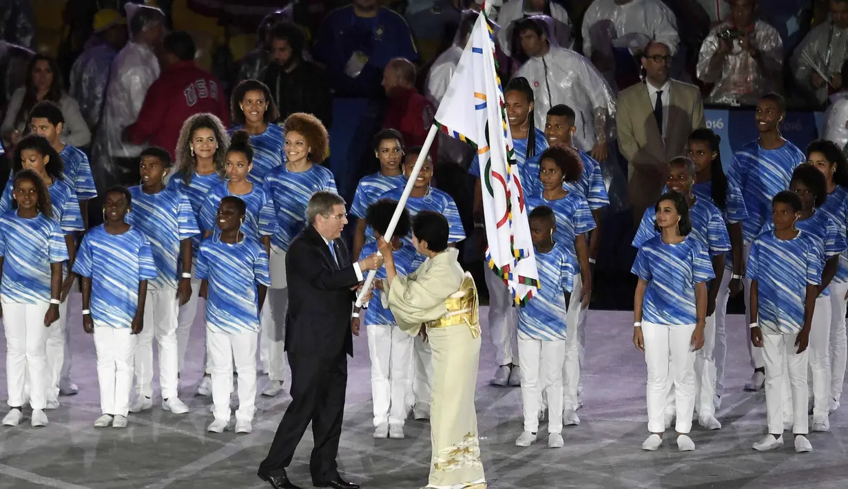 Presiden International Olympic Committee (IOC), Thomas Bach (kiri) memberikan bendra Olimpiade kepada Gubernur Tokyo, Yuriko Koike pada penutupan Olimpiade Rio 2016  di  Stadion  Maracana, Rio de Janeiro, (22/8/2016). (AFP/Eric Feferberg)