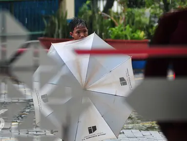 Seorang anak menunggu calon konsumen yang akan memakai jasa ojek payung, Jakarta, Selasa (1/11). Musim hujan dimanfaatkan sejumlah anak untuk mengais rezeki dengan mengojekkan payung. (Liputan6.com/Angga Yuniar)