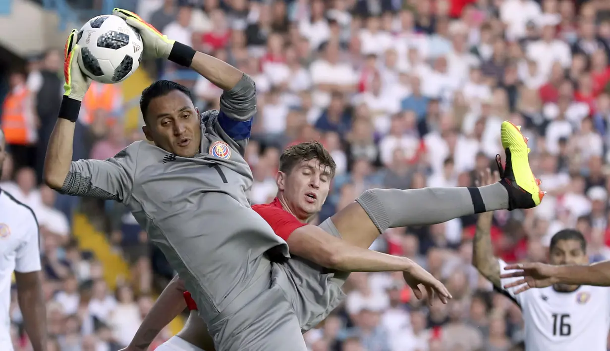 Kiper Kosta Rika, Keylor Navas mengamankan bola dari kejaran pemain Inggris, John Stones pada laga uji coba di Elland Road Stdium, Leeds, Inggris, (7/6/2018). Inggris menang 2-0.  (AP/Scott Heppell)