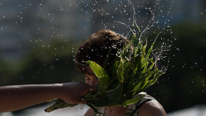 Seorang wanita diberkati dalam tradisi upacara penghormatan kepada Dewi Laut, Yemanja di pantai Copacabana, Rio de Janeiro, Sabtu (29/12). Penganut kepercayaan Afro-Brasil berkumpul di pantai menggelar ritual tahunan menjelang Tahun Baru. (AP/Leo Correa)