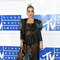 Rita Ora hadir dengan mengenakan busana rancangan dari Marc Jacobs. Gaun menerawang warna hitam yang dipadukan sedikit bulu-bulu di lengan dan bawah. Terlihat rambutnya dikuncir rapi ke belakang. (AFP / JAMIE MCCARTHY / GETTY IMAGES NORTH AMERICA)