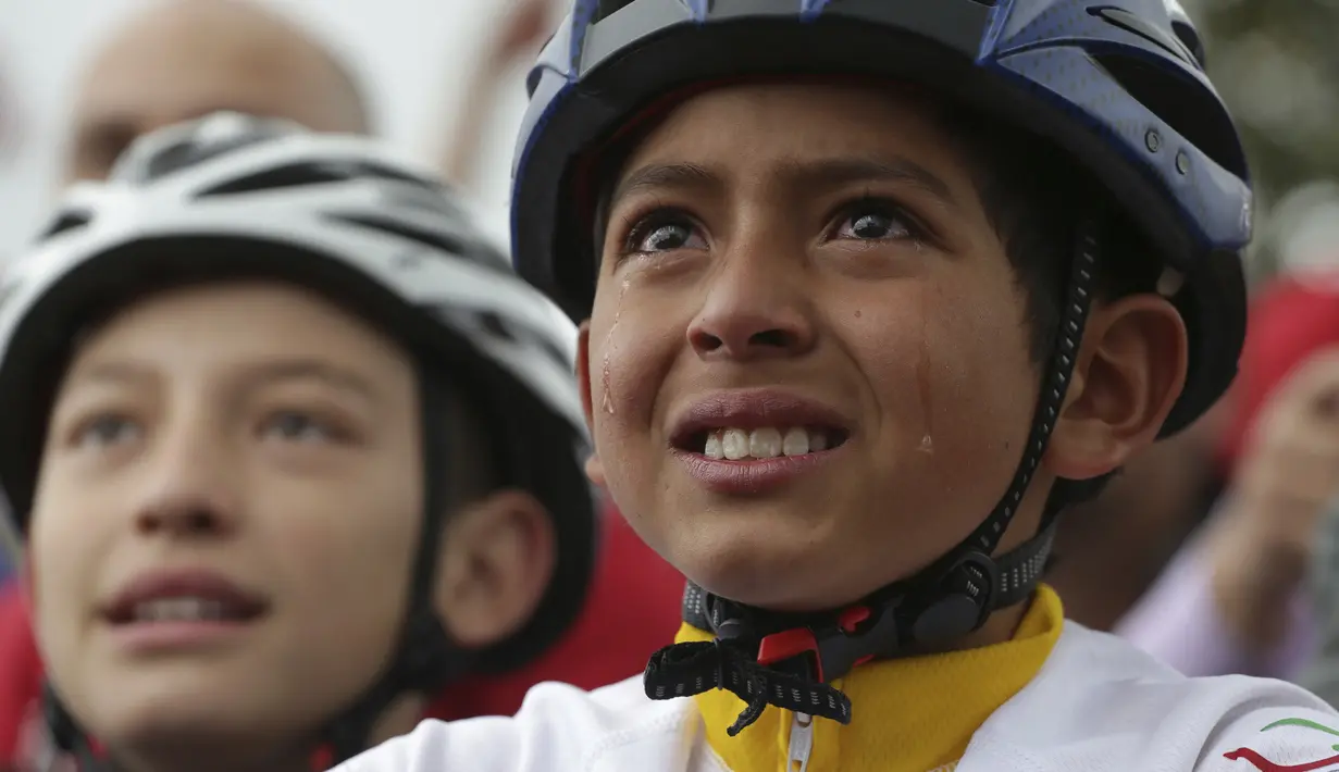 Air mata berlinang di wajah bocah Kolombia yang bahagia menyaksikan kemenangan Egan Bernal melalui layar besar di kota Zipaquira, Kolombia. (AP/Ivan Valencia)