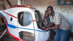 Felix Kambwiri dan temannya sedang menyelesaikan helikopter buatannya di garasi rumahnya di Desa Gobede, Malawi, 19 Februari 2016. Helikopter yang dikerjakan sejak empat bulan lalu itu dibuat dari rongsokan besi tua dan fiberglass. (Amos Gumulira/AFP)