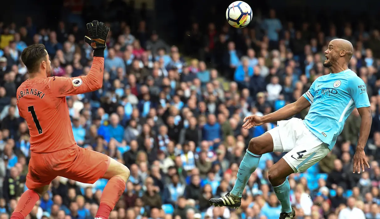 Pemain Manchester City, Vincent Kompany (kanan) mencoba mengecoh kiper Swansea City, Lukasz Fabianski pada lanjutan Premier League di Etihad Stadium, Manchester, (22/4/2018). Manchester City menang 5-1. (AFP/Paul Ellis)