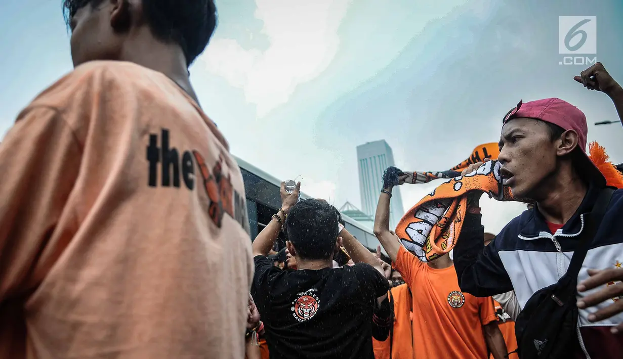 Suporter Persija bersorak saat menuju stadion Gelora Bung Karno, Jakarta, Minggu (9/12). Antusiasme ribuan suporter Persija bersiap mendukung tim kesayangannya bertanding melawan Mitra Kukar. (Liputan6.com/Faizal Fanani)