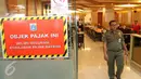 Petugas berjalan di samping stiker penunggak pajak yang dipasang di sebuah restoran di pusat perbelanjaan di kawasan Senayan, Jakarta, Senin (5/9). Pemasangan stiker dilakukan Dinas Pelayanan Pajak DKI lantaran menunggak pajak. (Liputan6.com/Angga Yuniar)