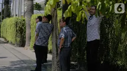 Sejumlah pria berdiri di bawah pohon selama gelombang panas di Jakarta, Selasa (22/10/2019).  BMKG memprediksi wilayah Indonesia akan mengalami panas selama kurang lebih satu minggu ini. Hal ini dikarenakan matahari yang berada dekat dengan jalur khatulistiwa. (Liputan6.com/Faizal Fanani)