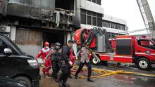 Api dengan cepat menyebar ke lantai 2, 3 hingga 6 dan asap pekat naik dengan cepat memenuhi tiap lantai di Gedung Terra Drone. Tampak dalam foto, personel dari Dinas Penanggulangan Kebakaran dan Penyelamatan mengevakuasi jenazah korban kebakaran di Jakarta, Selasa 9 Desember 2025. (AP Photo/Dita Alangkara)
