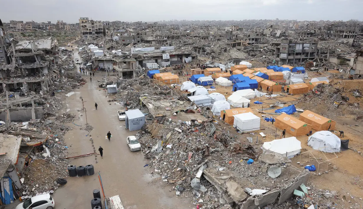 Warga Palestina yang mengungsi mendirikan tenda-tenda permukiman di tengah-tengah puing-puing bangunan yang hancur akibat serangan Israel. (Bashar TALEB/AFP)