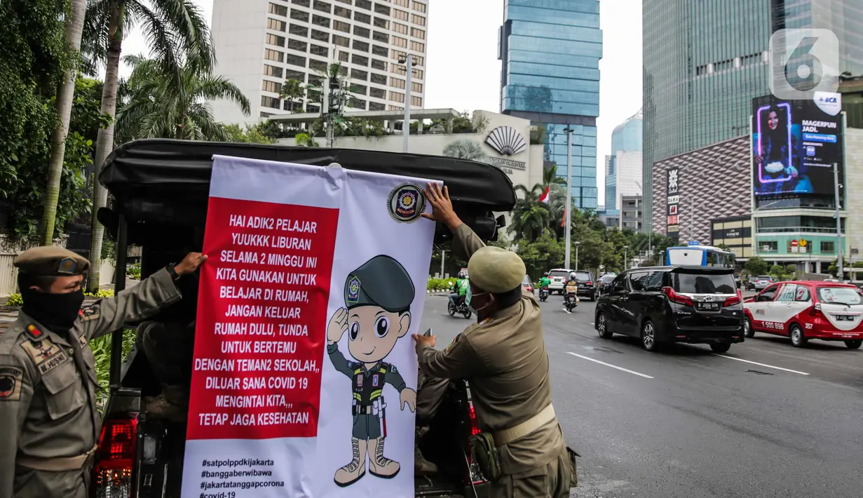Petugas Satpol PP memasang spanduk mini untuk memberikan imbauan sekaligus sosialisasi kepada masyarakat guna mencegah penularan Covid-19 di Bundaran HI, Jakarta, Kamis (19/3/2020). (Liputan6.com/Faizal Fanani)