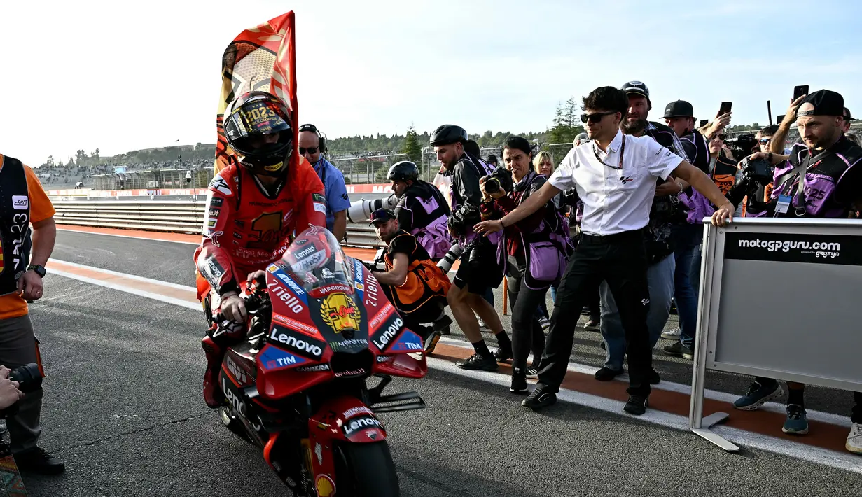 Pembalap Ducati Lenovo, Francesco Bagnaia, merayakan kemenagan dirinya sebagai juara dunia MotoGP 2023 setelah berhasil finis posisi pertama pada balapan MotoGP Valencia, Minggu (26/11/2023). (AFP/Javier Soriano)