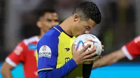 Pemain Al Nassr, Cristiano Ronaldo mencium bola sebelum menendang bola dari titik penalti ke gawang Al Wehda yang membuahkan gol dalam pertandingan lanjutan pekan ke-16 Liga Arab Saudi 2022/2023 yang berlangsung di King Abdulaziz Sports City Stadium, Jumat (10/2/2023) WIB. Kini Ronaldo telah mengemas lima gol dari empat pertandingannya bersama Al Nassr. (AFP)