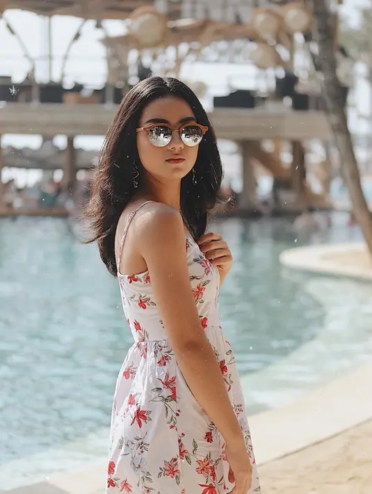 Pergi berlibur, memang paling cocok menggunakan pakaian dengan tema summer. Dress motif floral dengan warna cerah membuat penampilan Ersya lebih ceria. Aksesoris kacamata membuat penampilan gadis 19 tahun ini semakin kece. (Liputan6.com/IG/@ersyaurel)