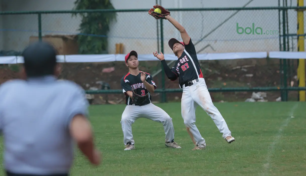 Dua pemain Singapura berebut bola saat melawan Indonesia pada laga Asian Softball Championship di Senayan, Jakarta,Selasa (25/4/2018). Indonesia menang atas Singapura 8-2. (Bola.com/Nick Hanoatubun)