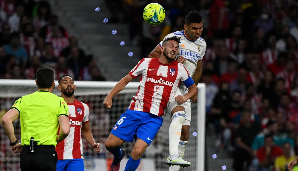 <p>Gelandang Atletico Madrid Koke (kiri) berebut bola dengan gelandang Real Madrid Casemiro dalam laga pekan ke-35 Liga Spanyol di Wanda Metropolitano, Senin (9/5/2022) dini hari WIB. Atletico Madrid berhasil menang dengan skor tipis 1-0 atas Real Madrid. (PIERRE-PHILIPPE MARCOU / AFP)</p>