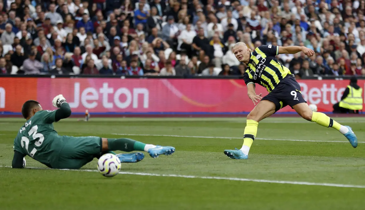 Pemain Manchester City, Erling Haaland (kanan) mencetak gol pertama timnya ke gawang West Ham United yang dijaga Lukasz Fabianski saat laga lanjutan Liga Inggris 2024/2025 di London Stadium, London, Inggris, Sabtu (31/08/2024) waktu setempat. (AFP/Ian Kington)