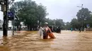 Seorang perempuan berjas hujan mengarungi jalanan yang tergenang banjir di Hue pada 28 Oktober 2025. Ribuan warga dievakuasi setelah curah hujan lebih dari 1.000 milimeter (mm) dalam 24 jam terakhir yang membanjiri kota di wilayah tengah Vietnam itu. (Foto oleh AFP)