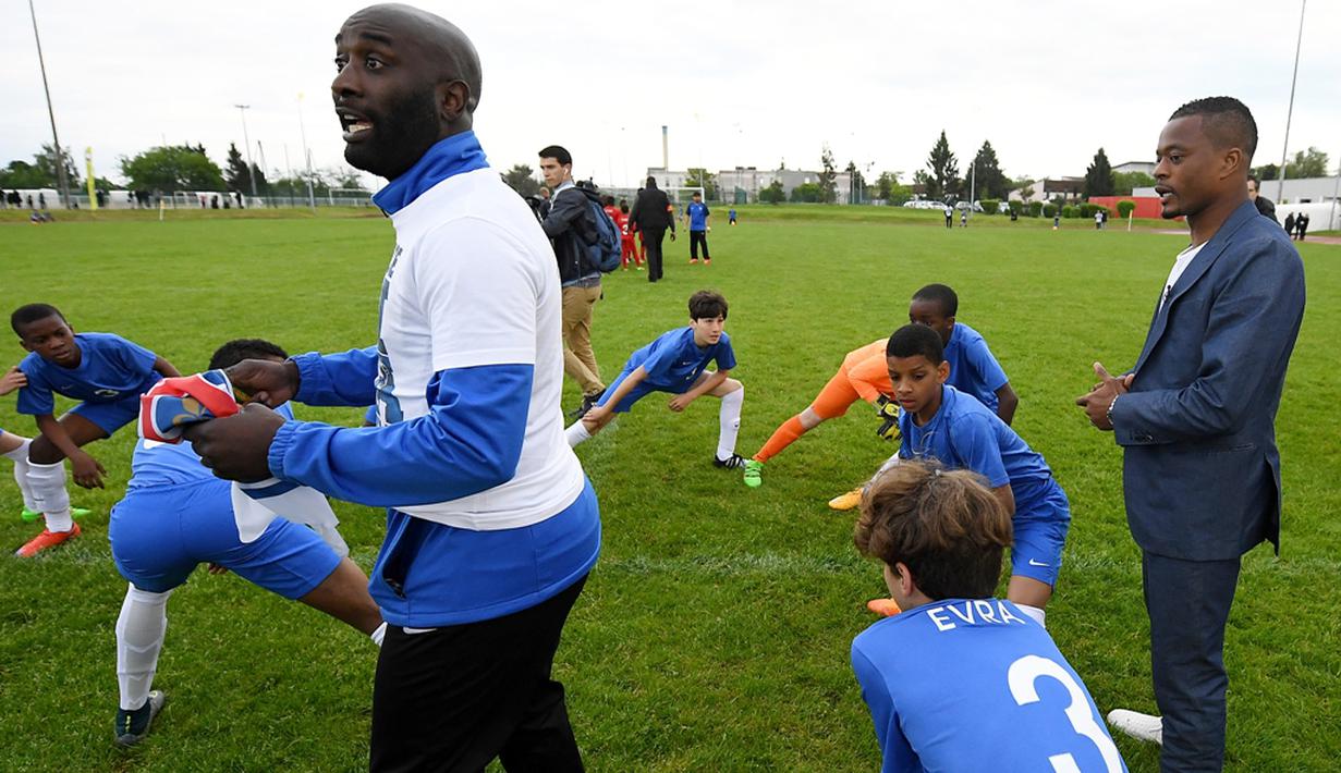 Pemain Timnas Prancis, Patrice Evra, memberi pengarahan kepada para pemain muda Les Ulis saat latihan ringan sebelum bertanding, (23/5/2016). (AFP/Franck Fife) 