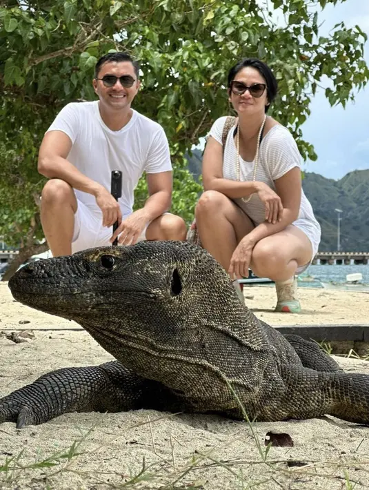 Berfoto bersama Komodo, Dian tampil dengan kaos bermotif garis-garis dipadu celana pendek dan sneakers. Lalu Anjasmara mengenakan kaos dan celana pendek putih. Credit: Instagram @bu_deedee