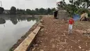 Seorang anak berjalan dekat tumpukan lumpur bercampur sampah dari proyek pengerukan situ Pedongkelan, Cimanggis, Depok, Rabu (28/11). Selain menimbulkan bau, banyaknya lumpur dan sampah membuat lingkungan warga tampak kumuh. (Liputan6.com/Herman Zakharia)
