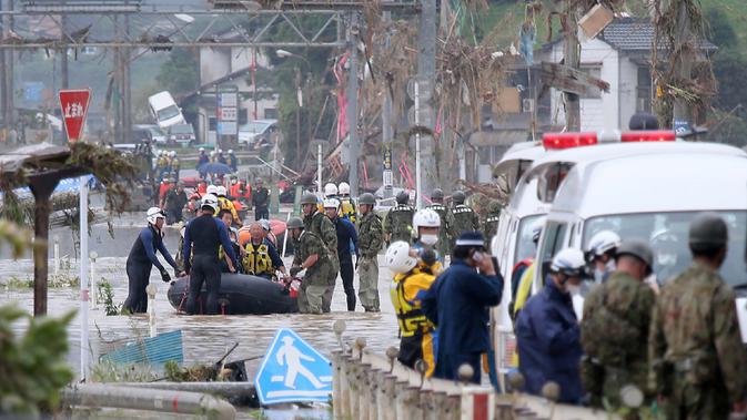 Warga dievakuasi dari daerah yang terkena banjir menggunakan perahu karet di Kuma village, prefektur Kumamoto, Jepang, Minggu (5/7/2020). Banjir yang memicu tanah longsor ini telah menghancurkan ratusan rumah dan kendaraan serta membuat jembatan antar kota terputus. (STR/JIJI PRESS/AFP)