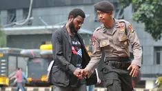 Mahasiswa Papua berjabat tangan dengan seorang polisi saat mendatangi Polda Metro Jaya, Jakarta, Selasa (1/12/2015). Kedatangan mereka untuk menunggu teman mereka yang diperiksa polisi (Liputan6.com/Yoppy Renato)
