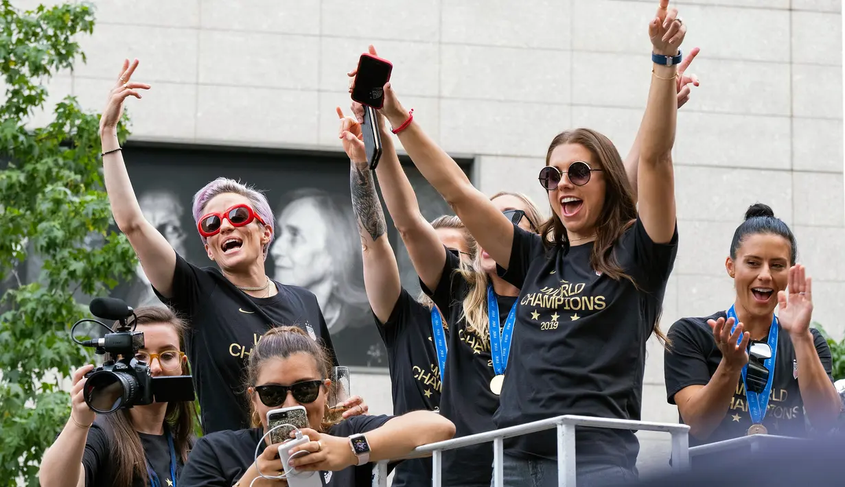 Pemain timnas sepak bola wanita Amerika Serikat (AS), Megan Rapinoe (kiri belakang) dan Alex Morgan (depan kanan) bersama rekan-rekan mereka menyapa warga saat parade kemenangan Piala Dunia Wanita 2019 di New York, AS, Rabu (10/7/2019). (AP Photo/Craig Ruttle)
