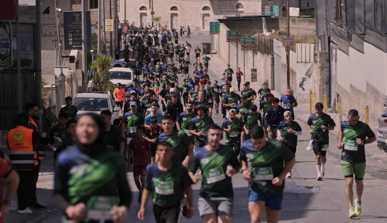 Maraton Internasional Palestina mengambil rute melintasi tembok pembatas, kamp pengungsi, dan situs-situs bersejarah di Bethlehem, Tepi Barat. Tampak dalam foto, para pelari berpartisipasi dalam Maraton Palestina di kota Betlehem, Tepi Barat, Jumat 8 Mei 2026. (AP Photo/Mahmoud Illean)