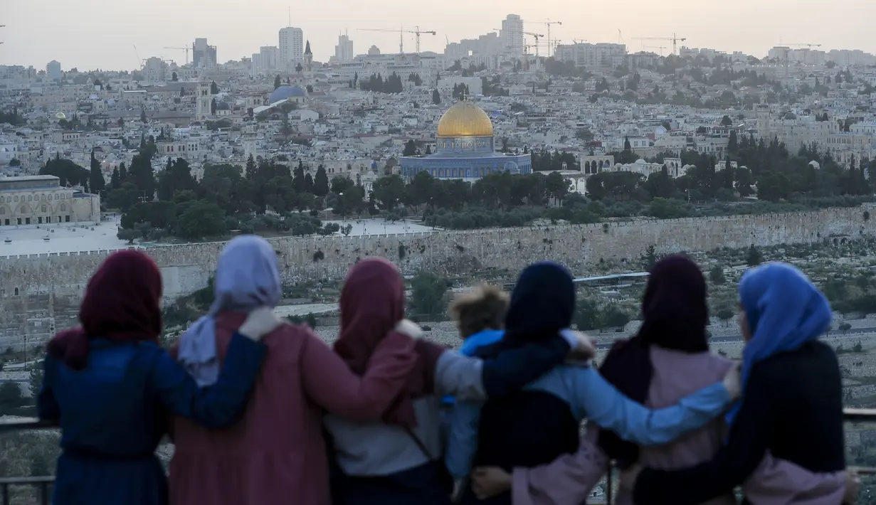 Warga Palestina berkumpul untuk berbuka puasa selama bulan suci Ramadan dengan latar belakang Kota Tua Yerusalem dan kompleks Masjid al-Aqsa yang ditutup selama krisis pandemi coronavirus yang baru di Bukit Zaitun (19/5/2020). (AFP/Ahmad Gharabli)