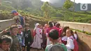 Sejumlah siswa menumpang truk di kawasan Cikoneng, Bogor, Selasa (30/3/2021). Untuk menuju sekolahnya di SDN Cikoneng, sebagian siswa harus menumpang truk, jalan kaki dan membawa kendaraan pribadi karena akses jalan yang sulit di daerah perbukitan perkebunan teh. (Liputan6.com/Herman Zakharia)