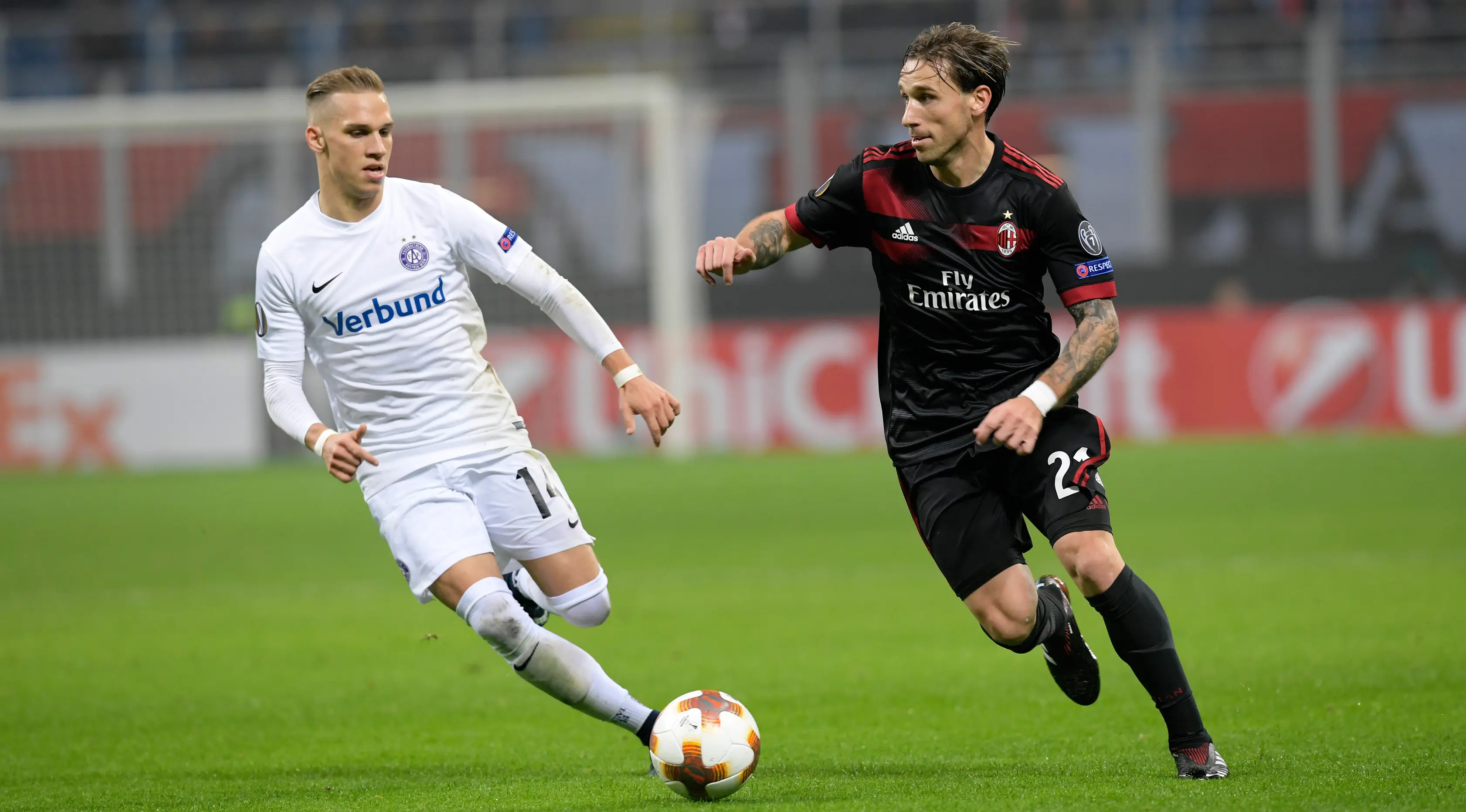 Gelandang AC Milan, Lucas Biglia berebut bola pemain Austria Wien, Christoph Monschein pada matchday kelima Liga Europa di Stadion San Siro, Jumat (24/11).   (MIGUEL MEDINA / AFP)