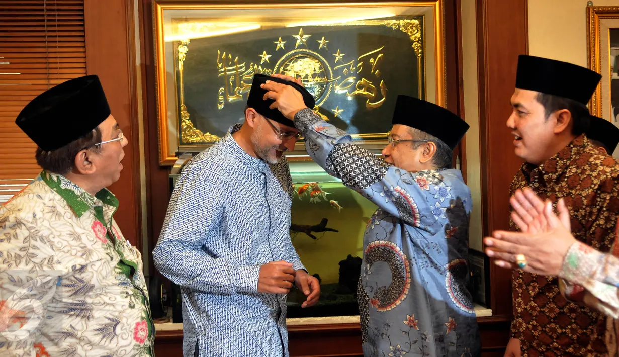 Ketua Umum PBNU, Said Aqil Siradj memakaikan peci ke Dubes Inggris untuk Indonesia, Moazzam Malik di Jakarta,  (8/4). Mereka berdialog masalah terorisme dan radikalisme dari sudut pandang NU sebagai organisasi Islam terbesar. (Liputan6.com/JohanTallo)