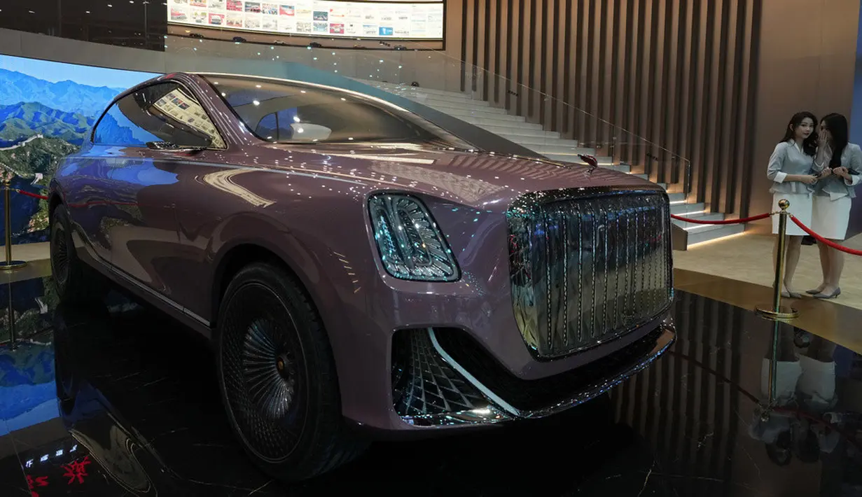 <p>Promotor saling berbisik dekat kendaraan konsep dari merek mobil mewah China Hongqi yang ditampilkan pada pameran Auto Shanghai 2023. (AP Photo/Ng Han Guan)</p>