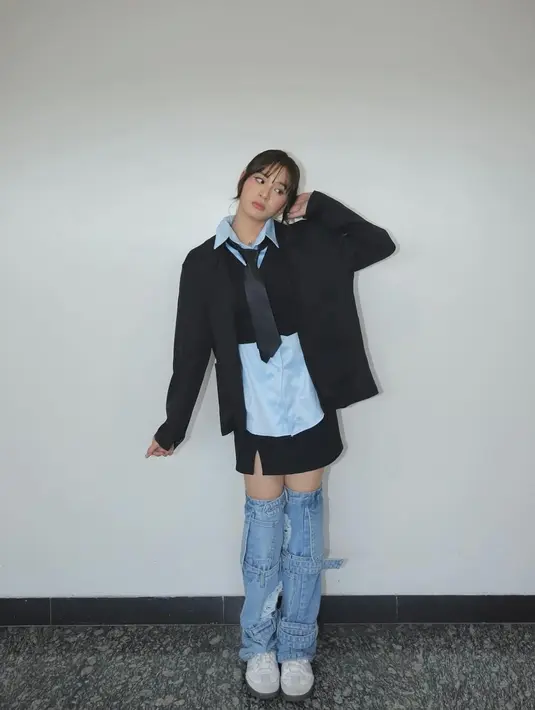 Padu padan edgy ala Zee JKT48. Ia mengenaakn oversized shirt berwarna biru, ditumpuk mengenakan cropped vest hitam, yang ditumpuk lagi dengan blazer hitam dan dasi hitam. Penampilannya semakin sempurna dengan mini skirt hitam dan denim attachment selutut, serta sneakers putih. [Foto: Instagram/jkt48.zee]