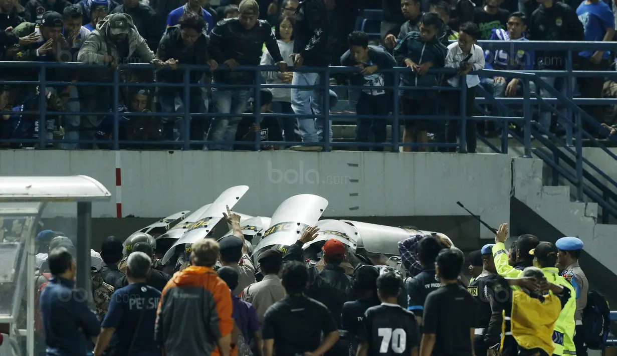 Petugas kepolisian melindungi pemain PSM dari lemparan botol usai pertandingan melawan Persib pada laga Piala Presiden di Stadion GBLA, Bandung, Jumat (26/1/2018). Persib takluk 0-1 dari PSM. (Bola.com/M Iqbal Ichsan)