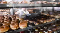 Pekerja mengemas donat dan kue kering untuk pelanggan di The Donut Man, Grand Central Market di pusat kota Los Angeles, AS, Jumat (11/3/2022). Ekonomi terbesar dunia itu terus dihantam oleh gelombang inflasi, yang diperkirakan akan memburuk akibat serangan Rusia ke Ukraina. (Patrick T. FALLON/AFP)