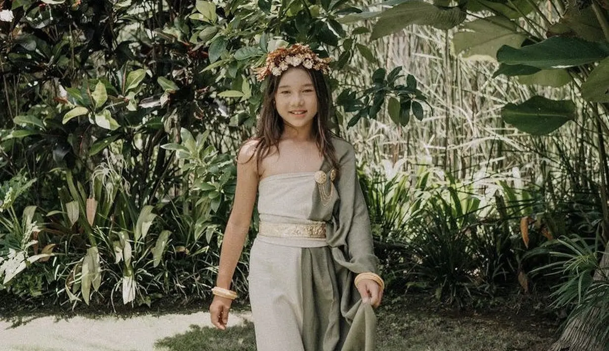 Kiyomi tampil elegan dengan kain yang hijau yang membalut dirinya. Dengan berbagai aksesori keemasan dari bros, belt, gelang, hingga riasan kepalanya. (@jenniferbachdim)