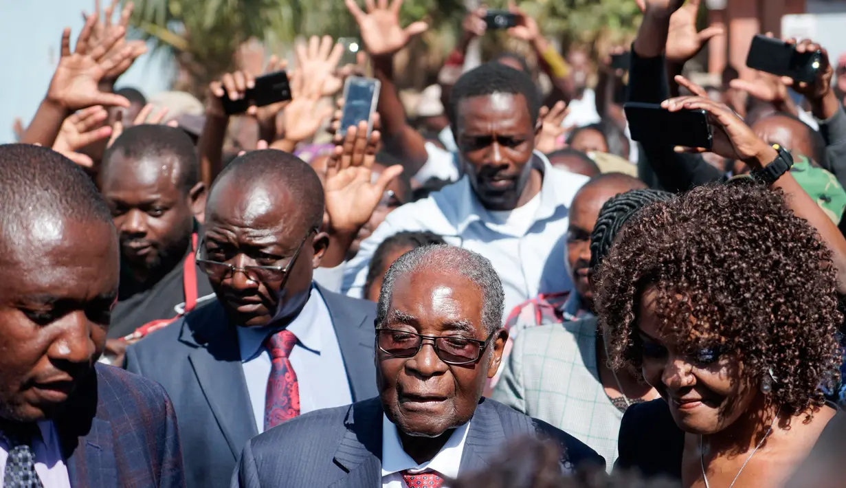 Mantan Presiden Zimbabwe, Robert Mugabe tiba untuk memberikan suara dalam pemilihan umum negara itu di TPS distrik Highfield, Harare, Senin (30/7). Mugabe memberikan suara di sebuah sekolah ditemani oleh istrinya, Grace. (AFP/Zinyange AUNTONY)