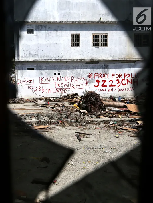 Tulisan cat merah dengan pesan Kami Rindu Rumah Kami dan tagar Pray for Palu menghiasi dinding rumah pasca gempa bumi dan tsunami di Jalan Trans Sulawesi, Palu, Sulawesi Tengah, Kamis (4/10). (Liputan6.com/Fery Pradolo)