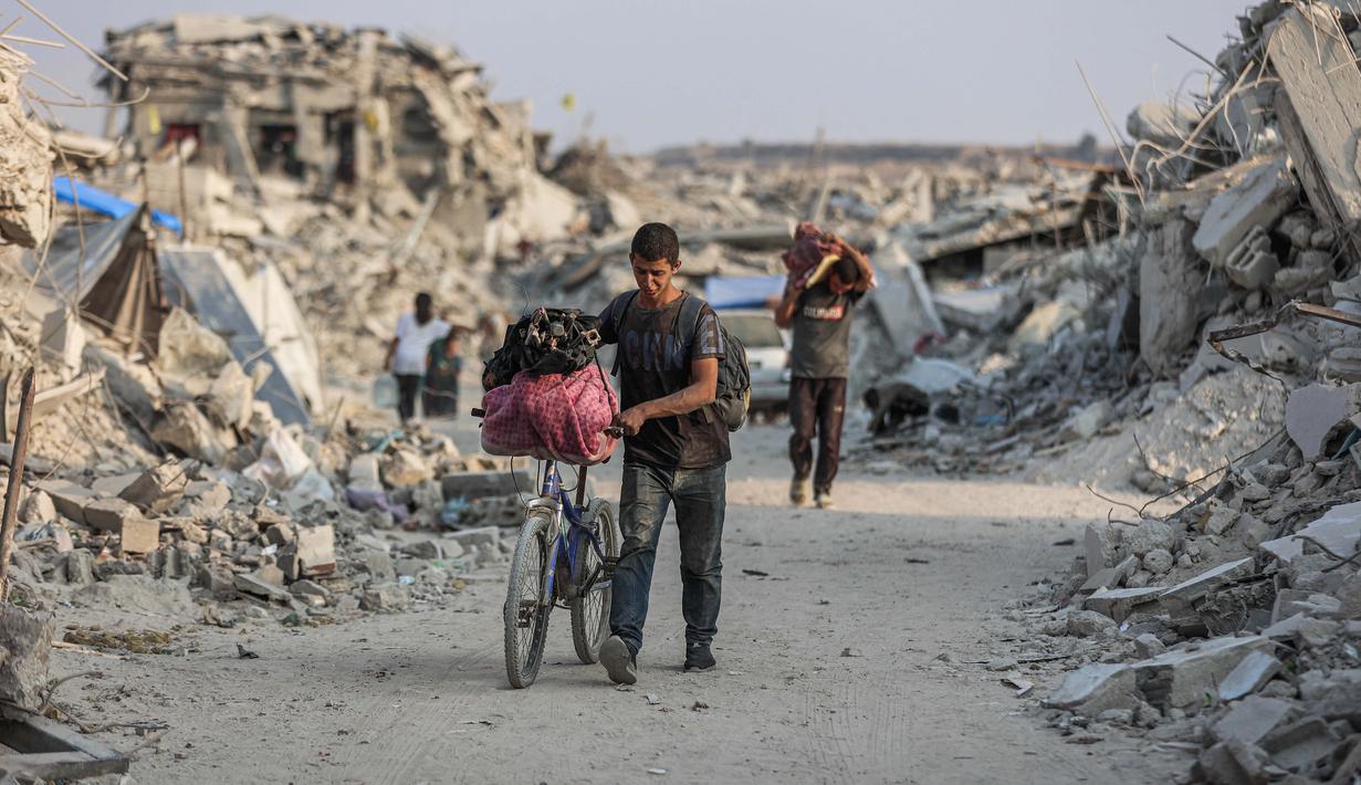 Seorang pria Palestina mendorong sepedanya di sepanjang jalan yang dikelilingi puing-puing bangunan yang hancur di Jabalia, di bagian utara Jalur Gaza, pada Jumat 7 November 2025. Perserikatan Bangsa-Bangsa (PBB) melalui Program Pangan Dunia (WFP) menyatakan pada Selasa 4 November bahwa mereka telah mendistribusikan paket makanan kepada sekitar satu juta orang di Jalur Gaza sejak gencatan senjata diberlakukan pada 10 Oktober 2025. (Omar AL-QATTAA/AFP)