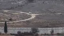 Israel berdalih bahwa tembok itu bagian dari rencana militer yang lebih luas, yang pembangunannya dimulai pada 2022 lalu. Tampak dalam foto yang diambil dari Israel, menunjukkan kendaraan Pasukan Sementara PBB di Lebanon (UNIFIL) yang sedang berpatroli di sisi Lebanon dari perbatasan yang memisahkan Israel utara dan Lebanon selatan pada 16 November 2025. (Jalaa MAREY/AFP)