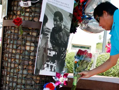 Seorang pria meletakkan karangan bunga di lokasi untuk mengenang kematian petinju legendaris Muhammad Ali, di Phoenix, Arizona, AS, Sabtu (4/6). Muhammad Ali meninggal pada usai 74 tahun setelah mendapatkan perawatan di RS. (REUTERS/Ricardo Arduengo)